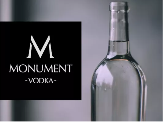 The picture shows the MONUMENT VODKA logo on the left and a photo of such a vodka bottle on the right. 